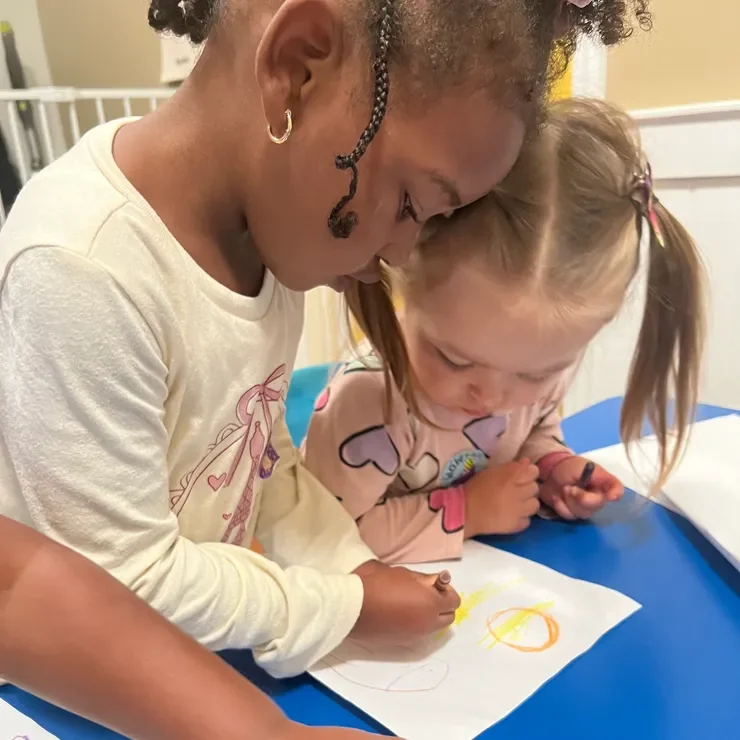 Two children drawing together at a table