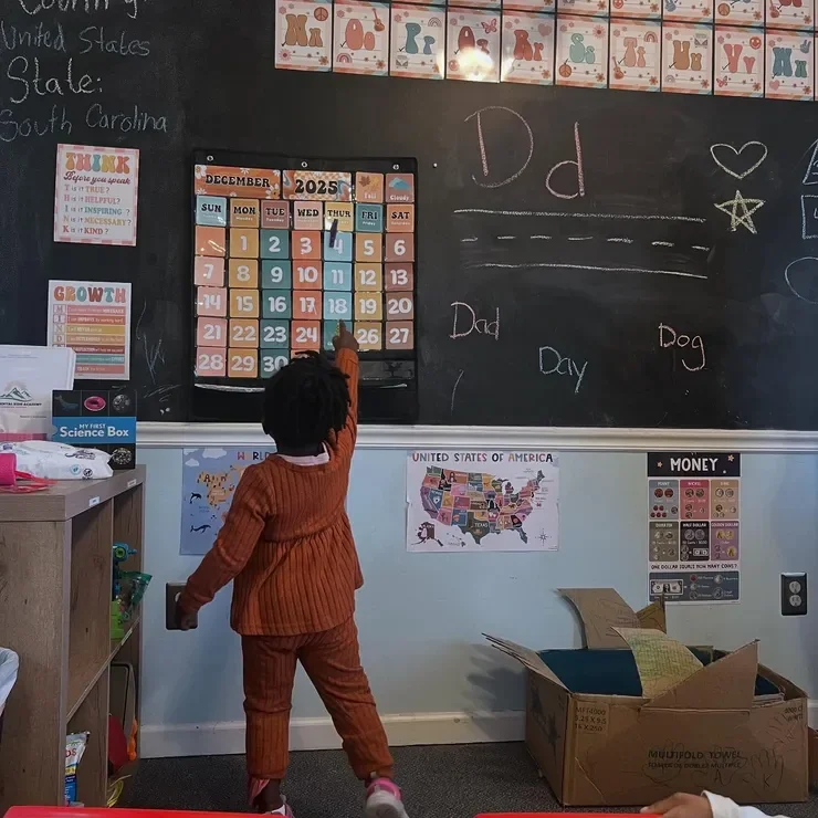 Child learning at the classroom calendar and chalkboard