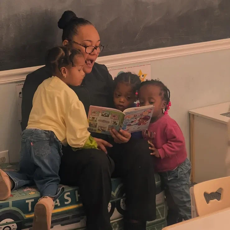 Teacher reading with children at Monumental Kids Academy